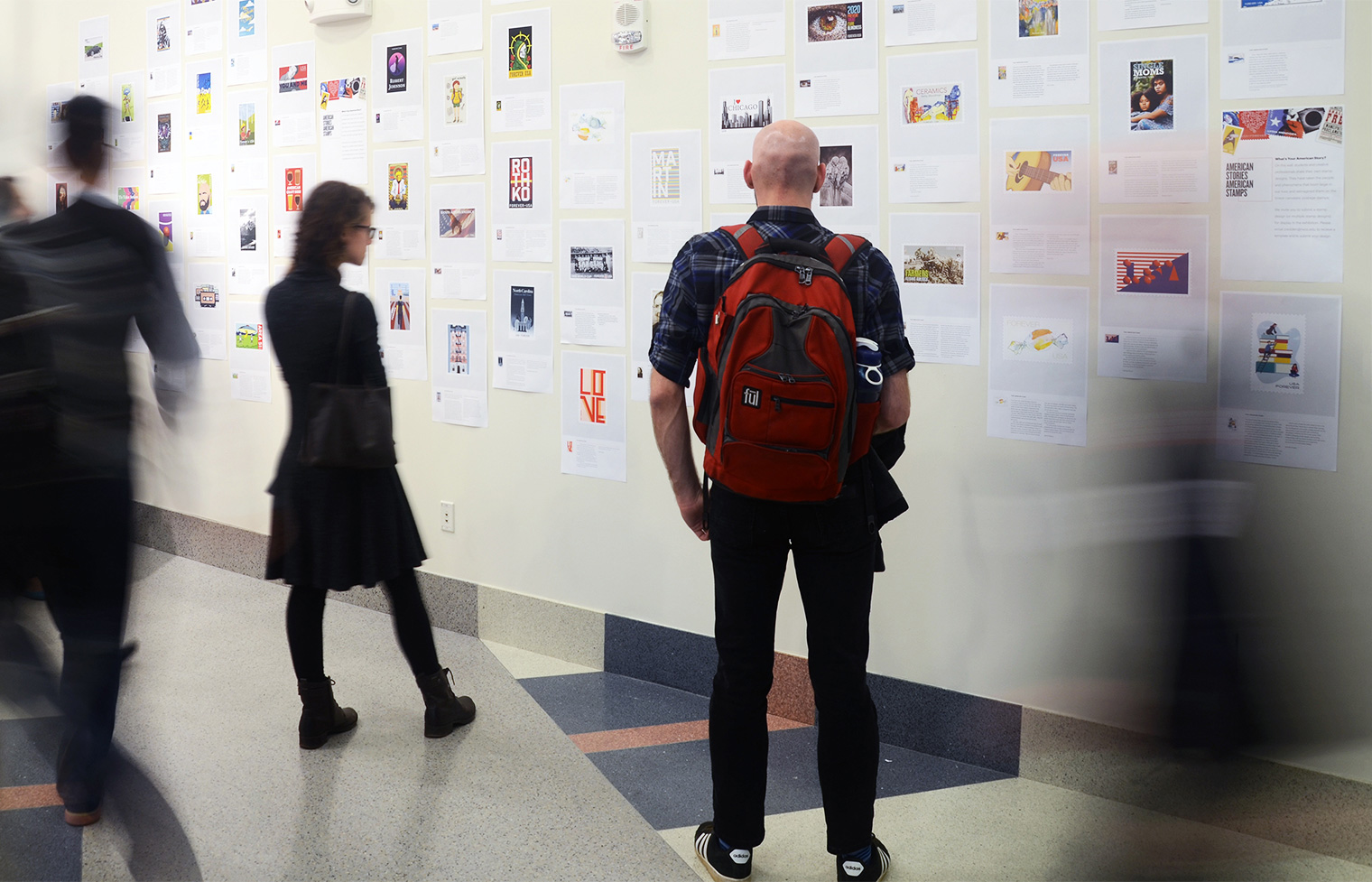 Visitors viewing the student stamp designs.