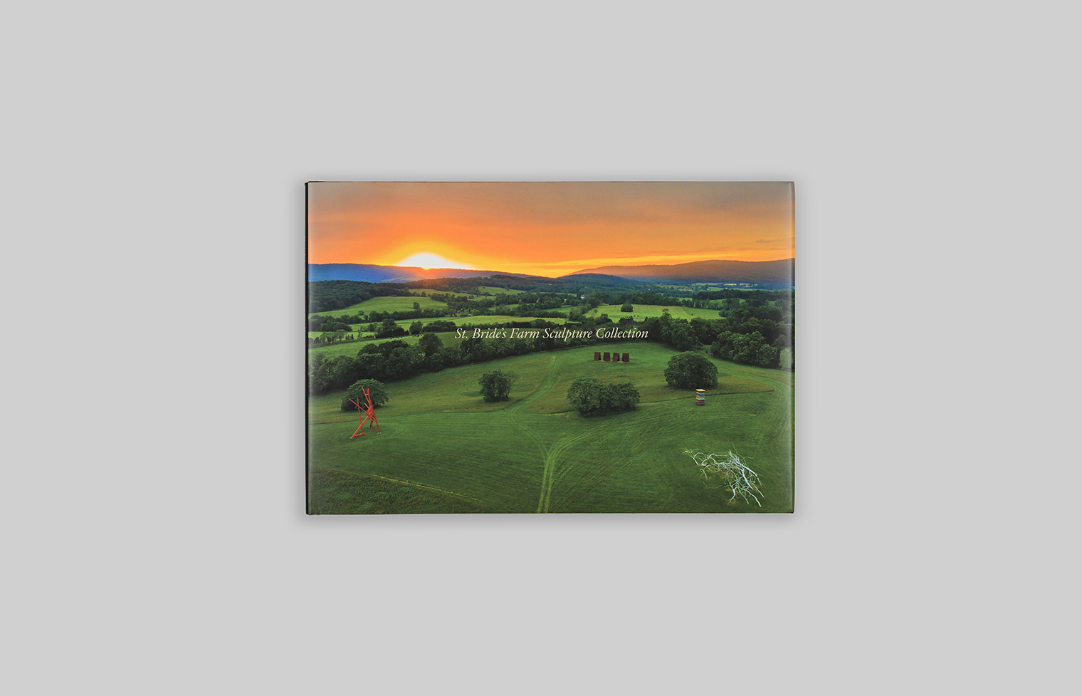 Cover features an aerial view of the countryside at sunset, with four sculptures in the foreground.