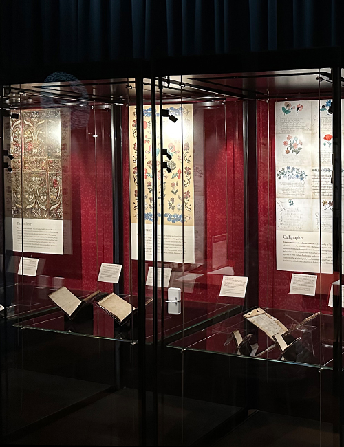 Glass display cases showcase Esther Inglis' books and panels detail the calligraphy and illustrative elements.