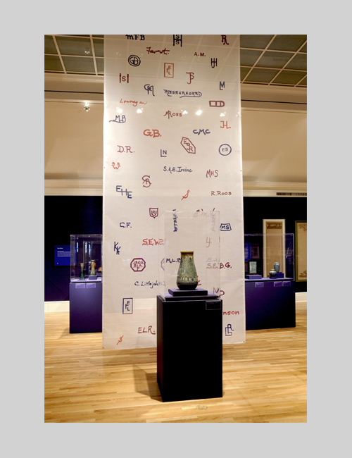 Exhibition photo for Women, Art, and Social Change: The Newcomb Pottery Enterprise shows pottery with a hanging banner.