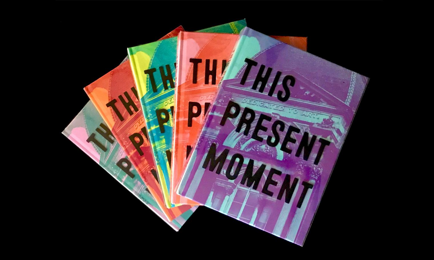 "This Present Moment," an exhibition that celebrates the Renwick's 50th Anniversary, has a cover with the title  in bold sans-serif letters over the face of a classically styled building with multiple versions in different color schemes displayed fanned out