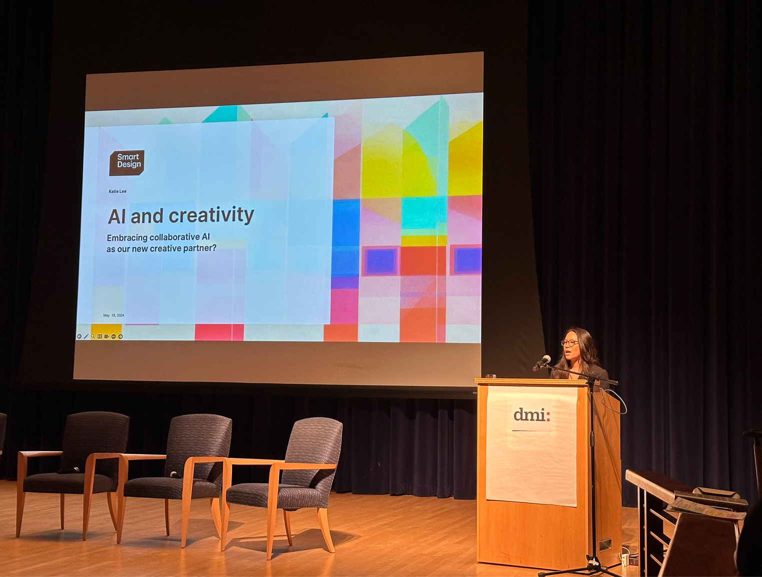 Katie Lee standing at a podium in front of a screen giving a presentation on AI and creativity at the Diversity in Design Conference
